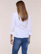 Camisa blanca de poplín de algodón, con silueta semi entallada, cuello camisero con escote en V y pechera frontal con plisado horizontal. Cuenta con abotonadura de strass plateado, mangas tres cuartos con puños anchos vueltos y paneles laterales elásticos.