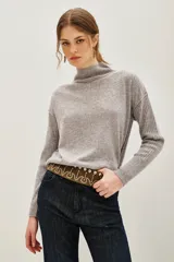 Polera de lana y cachemira color gris, con cuello alto y mangas largas con textura acanalada. Presenta un diseño holgado con aberturas laterales en el ruedo.