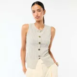 Camiseta de tirantes blanca con rayas sutiles, cuello redondo y cierre frontal de botones metálicos dorados martillados, con abertura inferior.