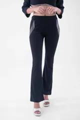 Pantalón negro de corte flare, tiro alto, con detalles de flecos de strass en los bolsillos laterales.