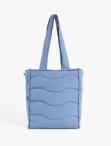 Cartera shopper azul acolchada con pespuntes ondulados. Tiene doble asa de hombro y correa extraíble regulable. Incluye cierre principal, bolsillo interior y bolsillo trasero con cierre.
