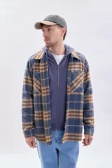 Sobrecamisa de franela a cuadros en tonos azul marino y marrón, con cierre frontal de botones, cuello camisero y bolsillos frontales con solapa.