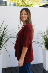 Sweater de punto color bordó, con cuello redondo, manga corta amplia y diseño holgado.