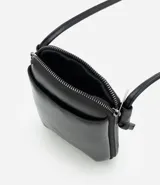 Cartera pequeña tipo porta celular de diseño compacto, confeccionada en poliuretano color negro. Cuenta con cierre de cremallera metálica, bolsillo frontal externo y correa fina ajustable para uso cruzado.