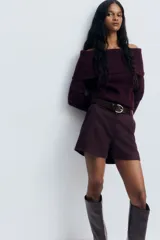 Buzo de punto trenzado con escote estilo off-the-shoulder y cuello ancho acanalado. Presenta mangas largas y terminaciones en punto acanalado en puños y bajo.