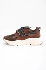 Zapatilla urbana de diseño chunky, combinando paneles de gamuza y cuero en tonos chocolate con malla técnica. Presenta cordones bicolores y una suela de plataforma de goma en color crema.