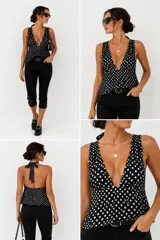 Top negro con estampado de lunares blancos, escote en V muy pronunciado, tirantes anchos y cierre de lazo ajustable en el cuello con espalda descubierta.