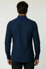 Camisa blanca de algodón, de diseño holgado y manga larga, con cuello camisero y cierre frontal de botones.