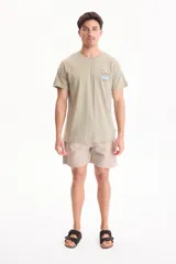 Remera verde claro de corte regular, con manga corta y estampa en la espalda que representa un paisaje de montañas, sol y una ola con la inscripción "est.96".