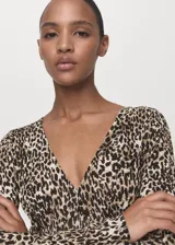 Vestido largo de diseño evasé con estampado animal print de leopardo. Presenta cuello en pico, mangas largas acampanadas y tejido plisado con cierre de cremallera lateral.