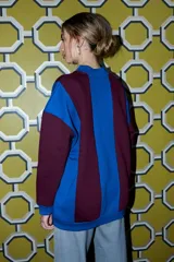 Buzo oversize de cuello redondo, con diseño patchwork en bloques de color azul eléctrico y bordó. Tiene puños y dobladillo acanalados en azul.
