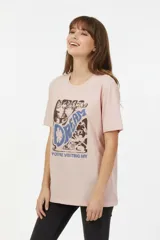 Remera de algodón color rosado, de corte holgado, con manga corta, cuello redondo y estampado frontal con la inscripción "Dream" y gráficos de gatos.