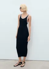 Vestido midi de punto fino en color negro, con diseño recto y cuello redondo. Presenta tirantes anchos con detalle de ribete en contraste en tonos blanco y tostado.