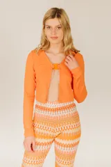 Top corto azul de tejido de punto acanalado, con mangas largas y cierre frontal con hebilla.