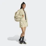 Campera tipo bomber Adidas Z.N.E. de corte holgado, color beige, con cierre frontal completo, cuello tipo béisbol y logo de las 3 barras en caucho mate en el pecho. Confeccionada en tejido ripstop con protección UV, presenta puños elásticos y diseño minimalista.