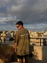 Remerón verde oliva con efecto gastado, corte holgado y estampado con texto en la espalda.