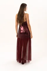 Vestido corto de tirantes finos en color bordó con acabado metalizado brillante. Presenta un corte recto ajustado al cuerpo y un detalle de volado en el ruedo confeccionado en tela traslúcida.