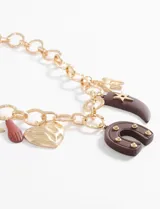 Collar con cadena gruesa dorada y dijes colgantes de corazón, estrella, herradura y cuerno.