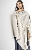 Ruana de punto color beige con sutiles motas multicolores, con bordes terminados en flecos largos.