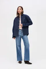 Camisa de algodón en color celeste claro, con cuello solapa, cierre frontal de botones y bordado pequeño en el pecho. Presenta un corte holgado y mangas largas.