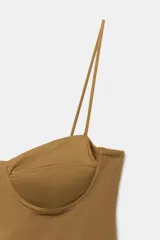 Vestido largo color tostado con diseño estilo corsé, escote corazón con aros y tirantes finos. Presenta un corte ajustado en la cintura con detalle de frunces laterales que aportan volumen a la falda.