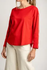 Sweater rojo de algodón con textura y corte oversize. Tiene mangas largas con dos rayas blancas en los brazos.