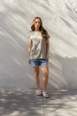 Blusa de corte holgado y manga corta con dobladillo, confeccionada en una mezcla de algodón y lino. Presenta un cuello redondo amplio y un diseño minimalista en color beige.