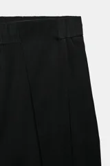 Pantalón tiro alto negro, con cintura elástica ajustable con cordones, bolsillos delanteros y detalle de pliegues en la parte frontal.