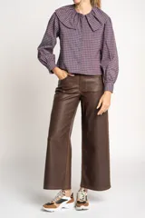 Camisa a cuadros azul y rosa con cuello babero, mangas largas abullonadas y cierre frontal con botones.