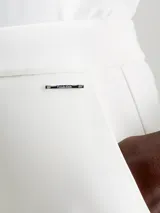 Pantalón blanco de pierna ancha confeccionado en tejido de punto técnico con poliéster reciclado y elastano. Presenta talle medio, pinzas delicadas en el centro de la pierna, bolsillos con ranura y barra de metal con logo de Calvin Klein debajo de la cintura.