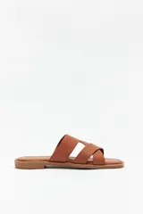 Sandalia plana color marrón con tiras anchas cruzadas, punta cuadrada y base levemente acolchonada.