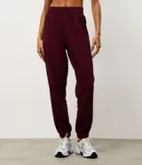 Pantalón jogger deportivo color bordó, con cintura elástica, bolsillos laterales y puños ajustados. Presenta recortes canelados en los laterales que aportan textura y diseño al modelo.