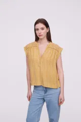 Blusa sin mangas de corte holgado, confeccionada en tela de viscosa con estampado de rayas verticales en tonos mostaza y blanco. Presenta cuello en V profundo y detalles bordados en los hombros.