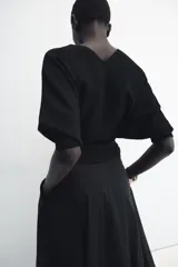 Jersey rojo de punto con escote en V pronunciado tanto en el delantero como en la espalda, mangas largas y diseño entallado en la cintura con caída acampanada.