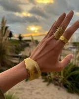 Brazalete rígido plateado con textura irregular.