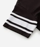 Remera deportiva de algodón color marrón con cuello en V y mangas cortas. Diseño overboxy con estampado de fútbol americano, lettering y rayas contrastantes en blanco.