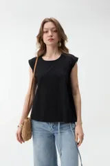 Remera negra sin mangas, de corte holgado, con hombreras marcadas y cuello redondo.