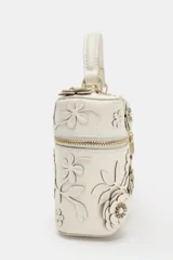 Bolso de mano formato vanity color crudo, con apliques de flores en relieve y hojas en el cuerpo. Cuenta con asa corta superior y cierre con cremallera doble dorada.