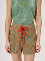 Short holgado de cintura alta con pretina integrada, cordón ajustable delantero y estampado geométrico en tonos rojos y beige.