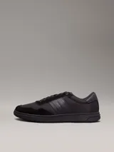 Zapatillas urbanas Calvin Klein de color negro, con detalles en cuero y gamuza. Presentan el logo de la marca en el lateral y suela de goma.