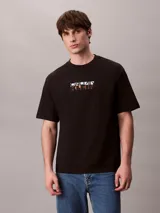 Remera Calvin Klein negra de corte relajado, manga corta y cuello redondo. Presenta un gráfico abstracto estampado en bloques con el logo de la marca en el pecho.