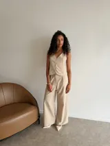 Chaleco de corte sastrero en tela tusor color beige con sutiles rayas verticales, escote en V y cierre frontal con botones al tono.