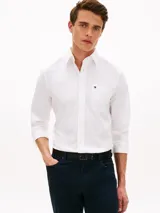 Camisa Tommy Hilfiger de corte regular, confeccionada en algodón Oxford elástico y ligero. Presenta cuello con botones, cierre frontal abotonado, mangas largas con puños redondeados y un bolsillo de parche en el pecho con el logo bordado.