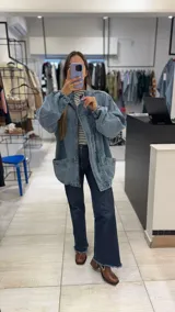 Campera de jean con diseño de monograma grabado, cuello alto, cierre frontal y puños elásticos. Presenta bolsillos frontales con solapa y botones metálicos.