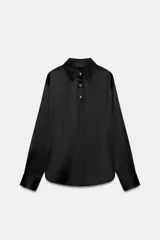 Camisa de corte clásico confeccionada en tejido satinado color negro, con cuello solapa, manga larga con puños rectos y cierre frontal mediante botones dorados.