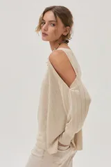 Top tejido color beige, de mangas largas y corte asimétrico con hombros descubiertos.