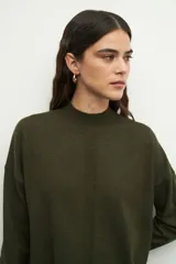 Polera negra de manga larga con puños elastizados, cuello alto y sutiles aberturas en los laterales.