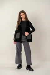 Chaleco de cuero negro con diseño sin mangas, corte recto y bolsillos frontales con contraste de textura. Presenta costuras visibles y un acabado artesanal.