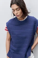 Chaleco tejido azul de calce relajado, silueta recta, cuello redondo, hombros caídos y diseño de punto con textura calada.