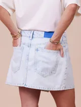 Minifalda de denim celeste con corte asimétrico y cierre con botón metálico.